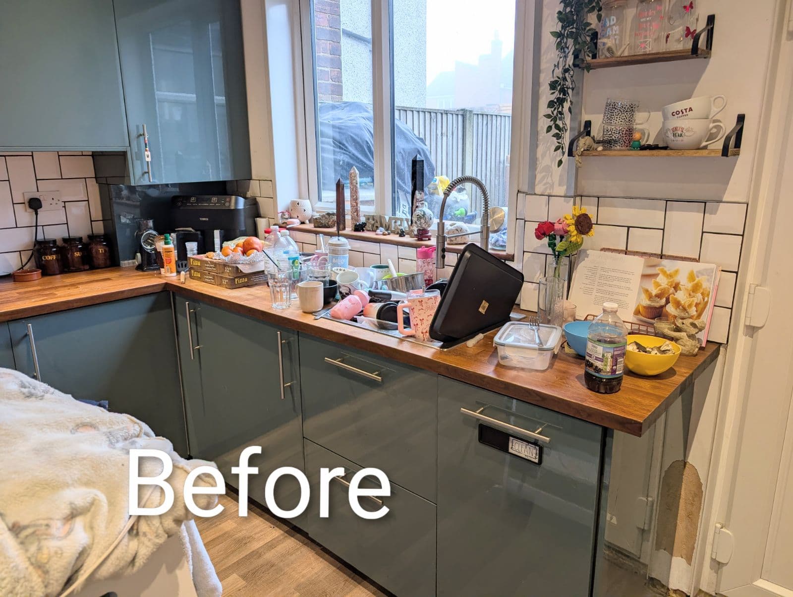 Kitchen sink and worktops piled with washing-up before cleaning