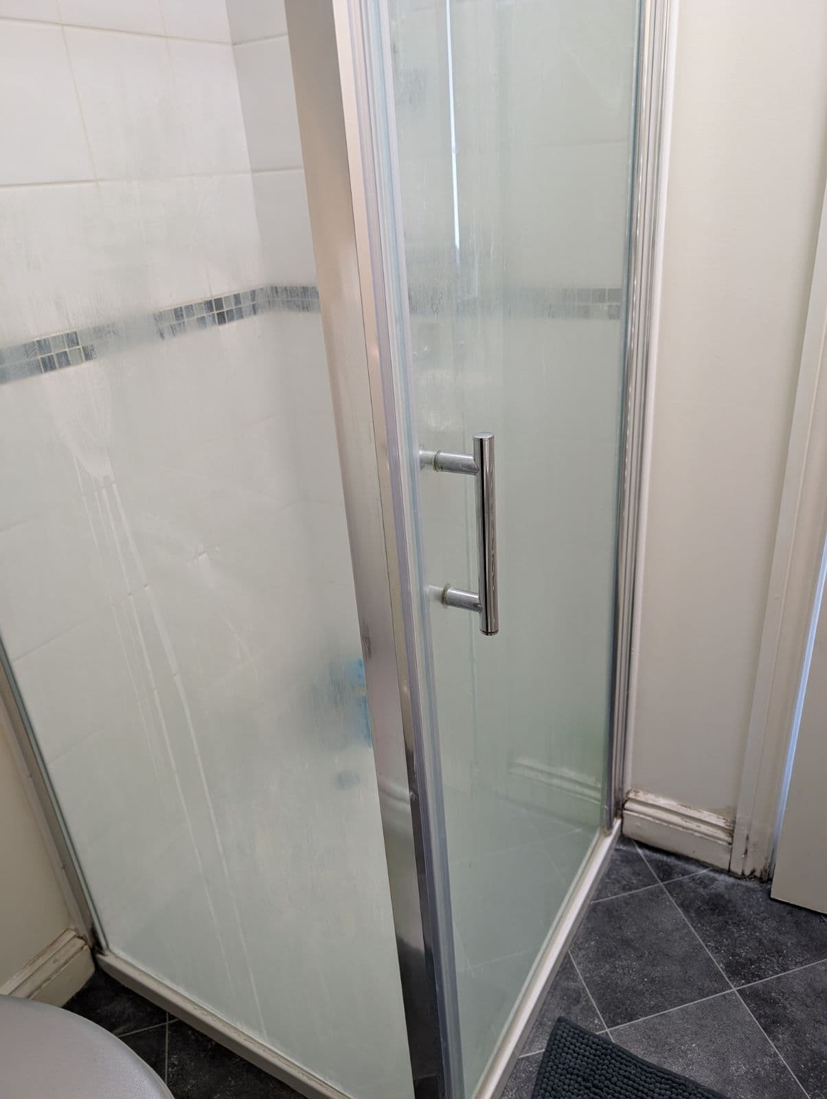 Shower screen clouded with limescale and soap scum before cleaning