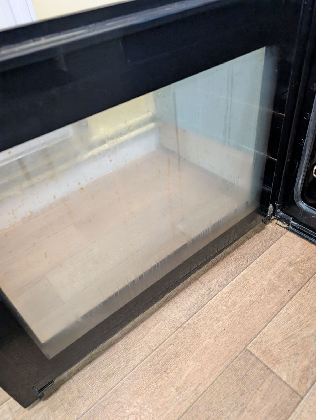 Black double-cavity cooker with greasy control panel before cleaning